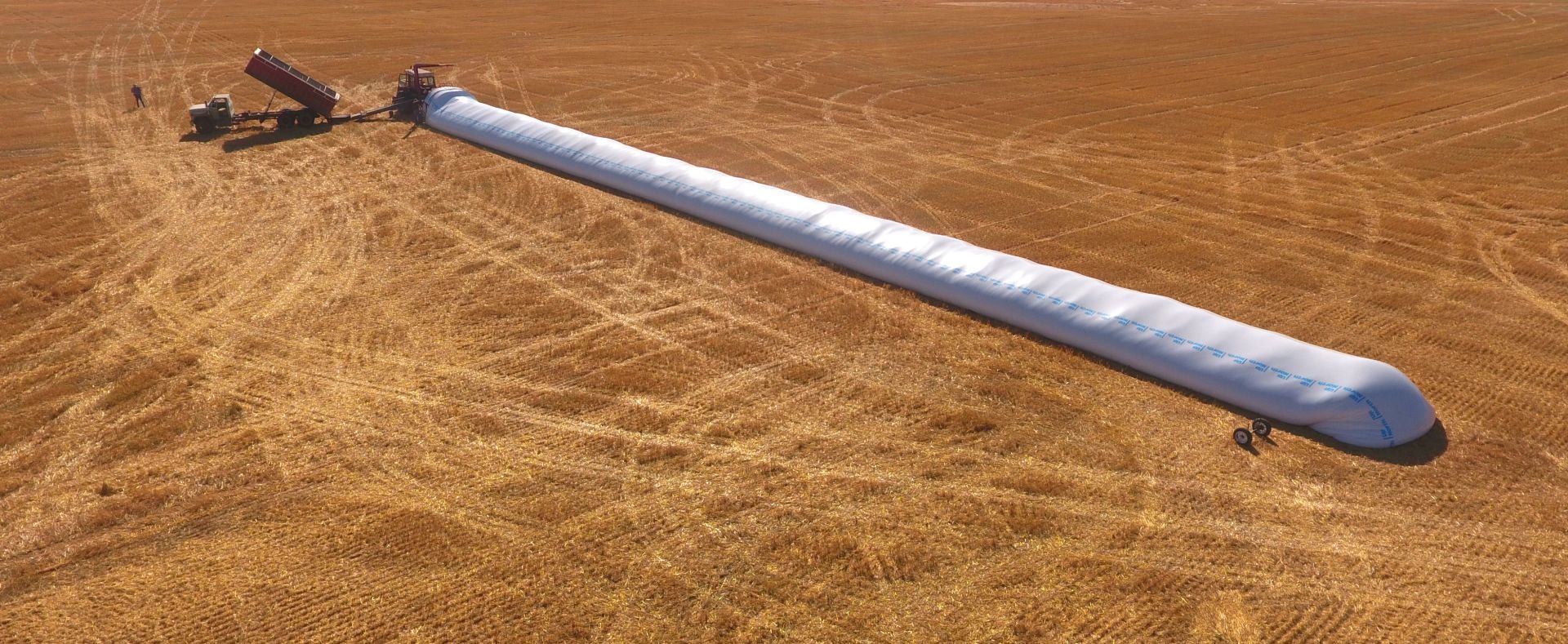 Aerial view of a grain bagger in the field during harvest